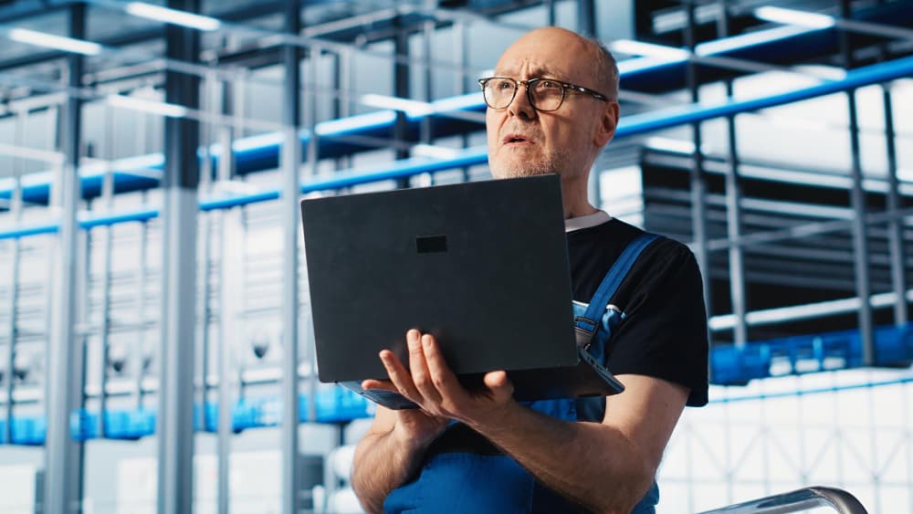 Mężczyzna w okularach trzyma laptopa